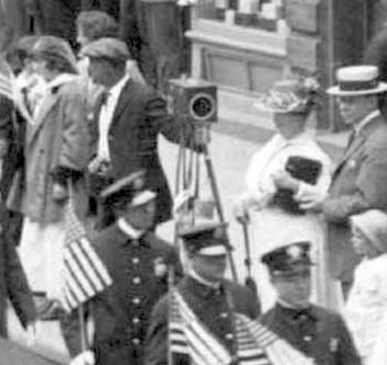 This photo might have been taken with a "box camera," which were popular in the arly part of the 20th century. The box camera in this photo was used to photograph the 1916 July 4th parade on Main Street in Nyack. Wikipedia says: A box camera is a simple type of camera, the most common form being a cardboard or plastic box with a lens in one end and film at the other. They were very popular in the late 19th and early 20th centuries. The lenses are often single element designs meniscus fixed focus lens, or in better quality box cameras a doublet lens with minimal (if any) possible adjustments to the aperture or shutter speeds. Because of the inability to adjust focus, the small lens aperture and the low sensitivity of the sensitive materials available, these cameras work best in brightly lit day-lit scenes when the subject is within the hyperfocal distance for the lens and of subjects that move little during the exposure. Eventually, box cameras with photographic flash, shutter and aperture adjustment were introduced, allowing indoor photos."