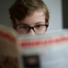 Young boy reading magazine, his face partially shown; magazine title obscured